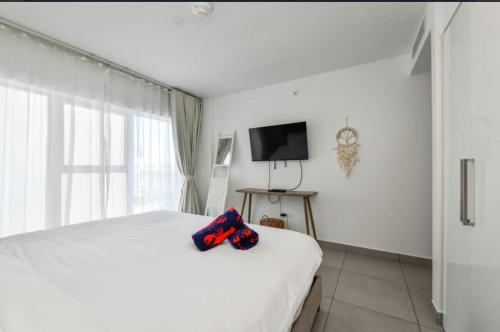 a white bedroom with a white bed and a television at Harbour House apt 410 in Oranjestad