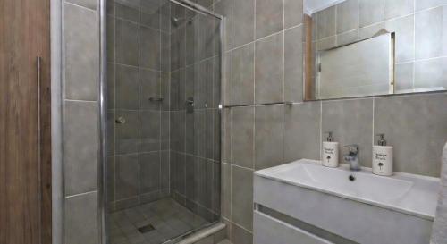 a bathroom with a shower and a sink and a mirror at Ballito Hill's Serenity Suite in Ballito