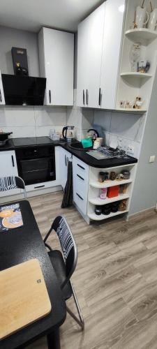 a kitchen with white cabinets and a table with a chair at Homestay Ezerkrasts in Liepāja