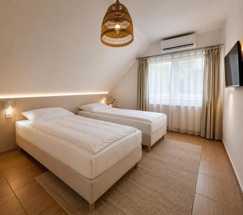 a bedroom with two beds and a window at Munkácsy Apartmanok in Balatonfenyves