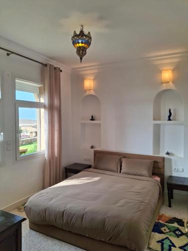 a bedroom with a bed and a window and a chandelier at Villa sur la plage in Tiznit