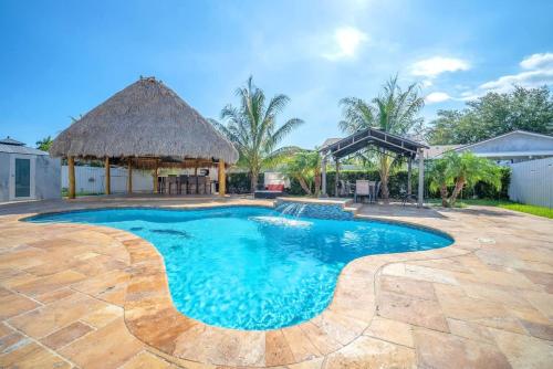 a swimming pool in a backyard with a thatch roof at 6BR Villa Tropical Haven Private Pool & BBQ in Homestead