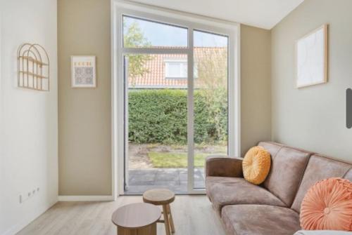 a living room with a couch and a large window at Sea & Forest Lodge in Oostkapelle