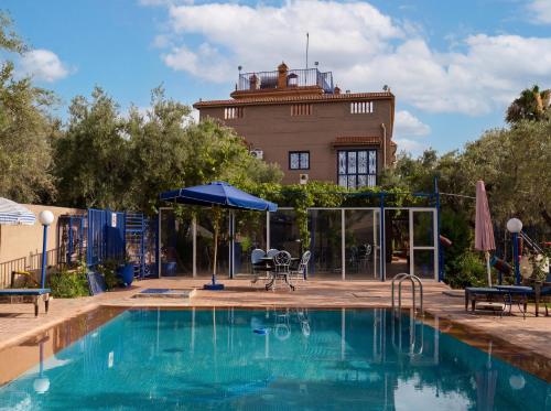 a swimming pool with a building in the background at Eco Farm Tayssir Marrakech in Marrakesh