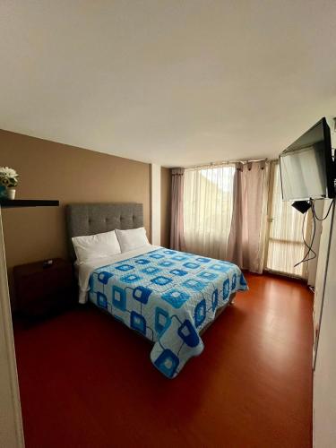 a bedroom with a bed with a blue and white blanket at Apartamento Completo Sector Exclusivo De Zipaquirá in Zipaquirá