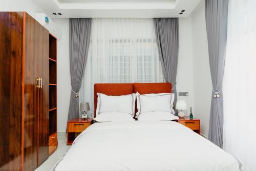 a bedroom with a large white bed and a window at Residence Cottages in Morogoro