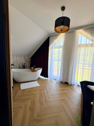 a bathroom with a white tub in a room with windows at Domek Veron 2 in Hańczowa