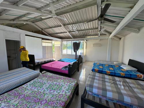 a room with three beds and a person standing in it at Casa Finca pasadia cerete in Cereté