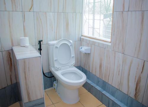 a bathroom with a toilet and a window at Musituni Luxury Villas in Diani Beach