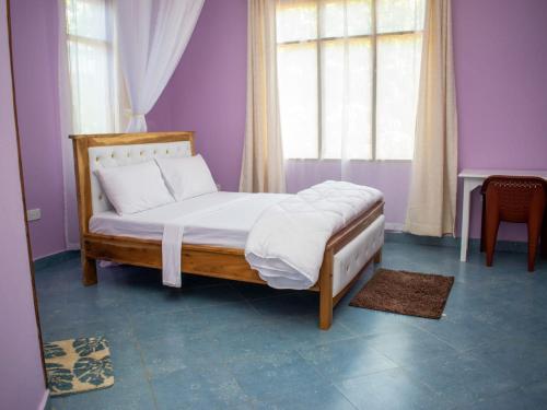 a bedroom with a bed with purple walls and a window at Musituni Luxury Villas in Diani Beach