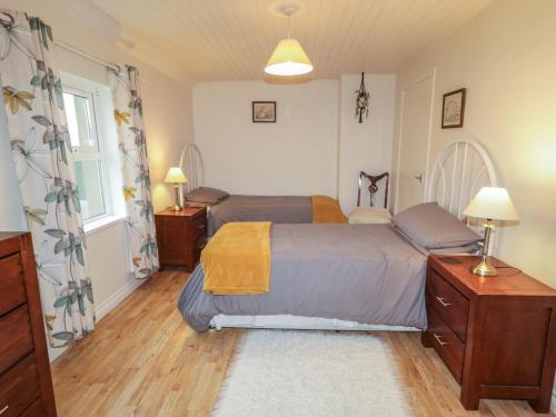 a bedroom with two beds and a window at Shaws Hill Farmhouse in Ballymena
