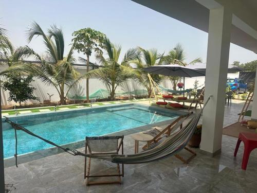 a hammock and chairs next to a swimming pool at Ker Ar Mor - Villa 3 chambres avec piscine privée à Nguerigne in Sintiân