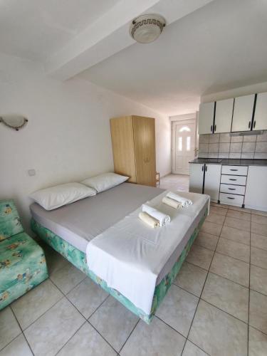 a bedroom with a large bed and a kitchen at Apartments Šešo B in Pag