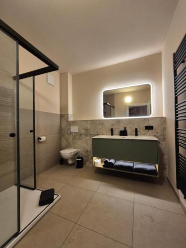 a bathroom with a sink and a toilet and a mirror at LINDENGUT - Boutique Hotel nahe IKUNA Park in Natternbach