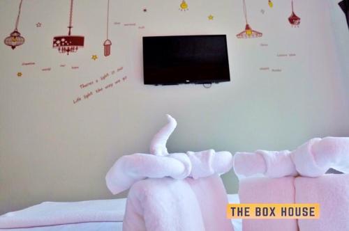 a bedroom with a bed with a toy elephant and a tv at The Box House in Krabi