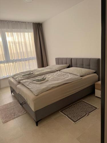 a large bed in a room with a window at Panoráma apartman in Dolný Čepen