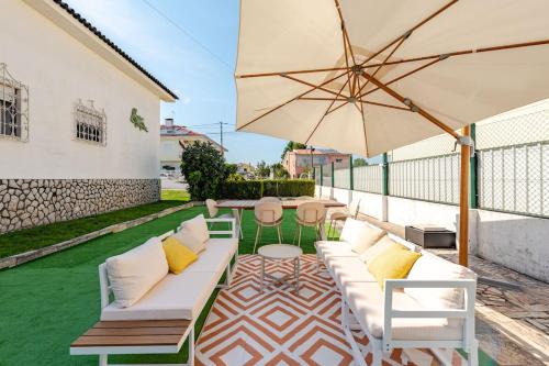 a patio with a white couch and an umbrella at The Quinta & Studios in Quinta do Conde