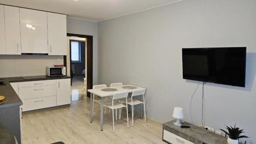 a kitchen with a table and a tv on a wall at Jedenastka in Płock