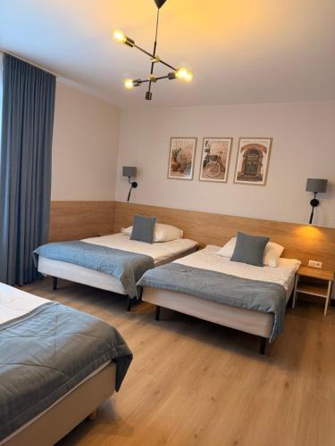a bedroom with two beds and a chandelier at Pokoje De Luxe Figaro in Płock