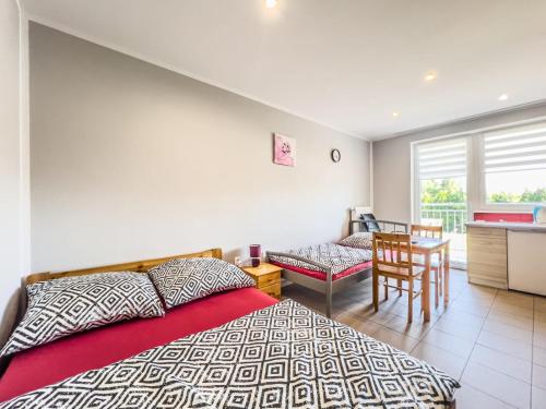 a bedroom with a bed and a table and a kitchen at Pensjonat Viki in Sarbinowo