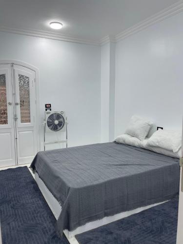a white bedroom with a bed with a blue rug at Chez Cat & Lolo in Quseir