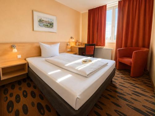 a hotel room with a large bed and a chair at Hotel Rhein-Ruhr by Mayburgh Bottrop Hauptbahnhof in Bottrop