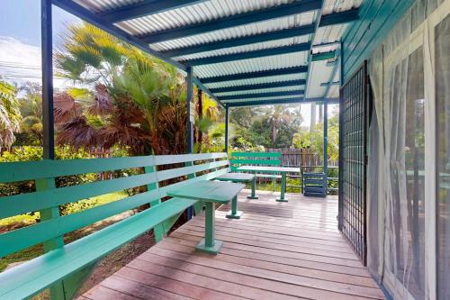 a deck with green benches on a building at Casita in Placencia