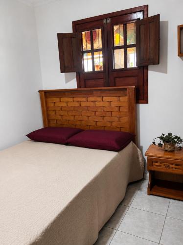 a bedroom with a bed with a wooden headboard and windows at Chácara Aconchegante com Piscina e Churrasqueira Perto do Ponto Turístico de Bezerros in Bezerros