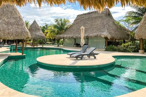 a swimming pool with two lounge chairs and thatched umbrellas at The Reserve in Dangriga
