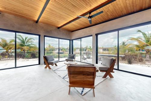 a large living room with a ceiling fan and windows at Seabird - Villa 26 in Placencia