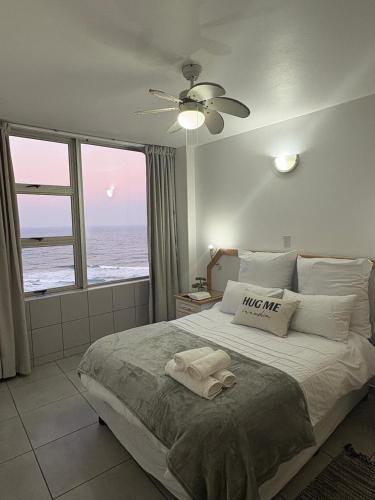 a bedroom with a bed with a view of the ocean at Oceans Whisper 704 beach apartment gated & Lift access in Scottburgh