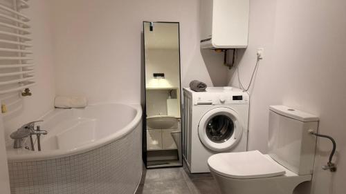 a bathroom with a tub and a washing machine at Targówek Home in Warsaw