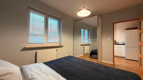 a bedroom with a bed and two windows and a kitchen at Targówek Home in Warsaw