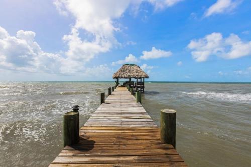 a wooden pier with a straw hut on the water at Bougainvilla in Placencia