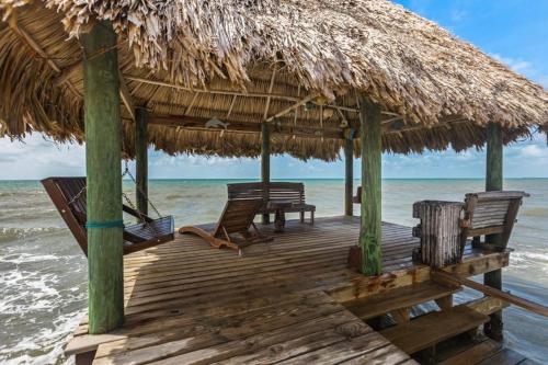 a wooden deck with chairs and a thatched umbrella on the beach at Bougainvilla in Placencia