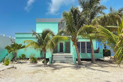 a blue house on the beach with palm trees at Villa 18 at Maralaguna in San Pedro