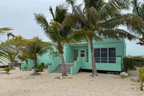 a blue house on the beach with palm trees at Villa 18 at Maralaguna in San Pedro
