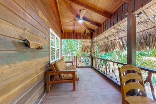 a porch of a cabin with a ceiling fan and a chair at Bungalow Bobo in Placencia
