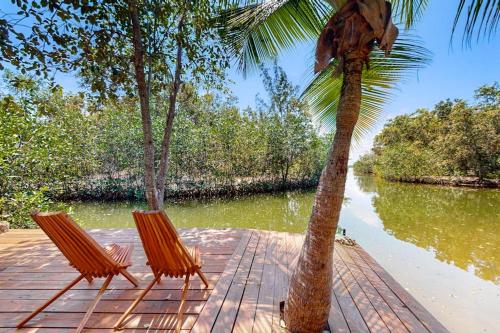 two chairs sitting on a dock next to a palm tree at Bungalow Bobo in Placencia