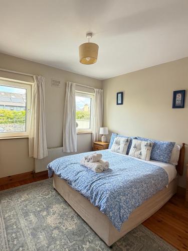a bedroom with a bed with a blue comforter and two windows at Glebe cottage in Kinvara