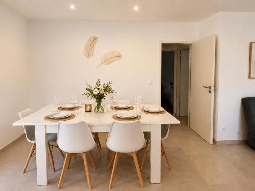 a white dining room table with white chairs and flowers at Villa T4 Cosy entre Mer, Montagne & Espagne avec Jardin, Billard & Barbecue in Thuir