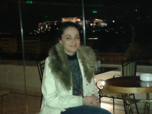 a woman in a white coat sitting at a table at Hotel Dryalos in Miléai
