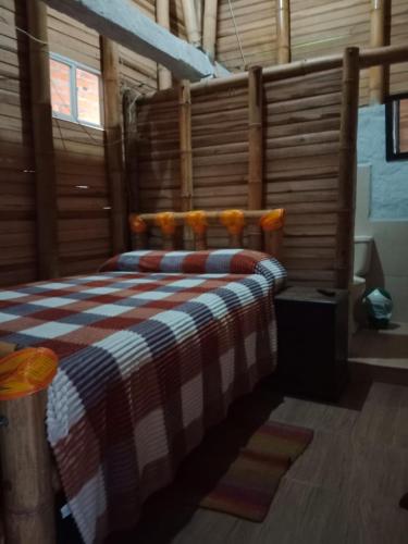 a bedroom with a bed with a checkered blanket at Hospedaje Los Tumbilos in Silos