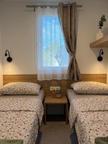 two twin beds in a room with a window at Camping Matija in Betina