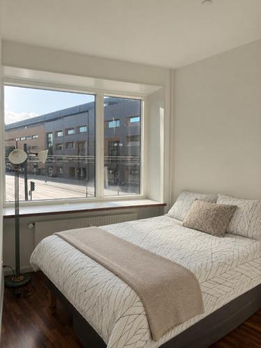 a bedroom with a bed and a large window at NØ -Central Apartment Odense C in Odense