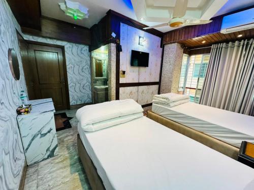 a room with two beds and a tv in it at Sea Shell Service Apartment in Bāiljuri