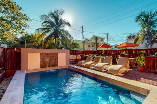 a pool with chaise lounge chairs next to a fence at Family Getaway Suite at Hummingbird Home Suites Gold Standard Certified in San Pedro