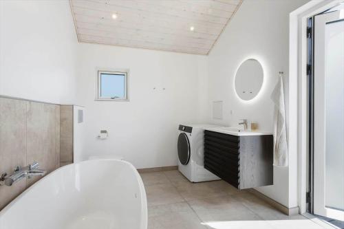 a white bathroom with a tub and a sink at TV1737-Bindslev-Mellemklitvej-23 in Tversted