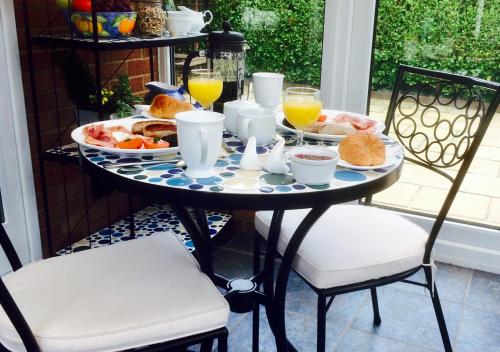 uma mesa de pequeno-almoço com alimentos de pequeno-almoço e sumo de laranja em Stepping Stones B&B em Lymington