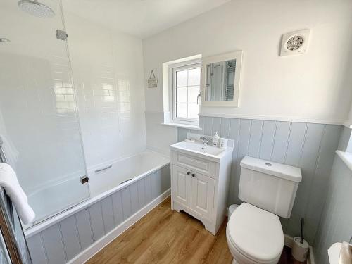 a bathroom with a toilet and a tub and a sink at Barn Cottage in Minehead